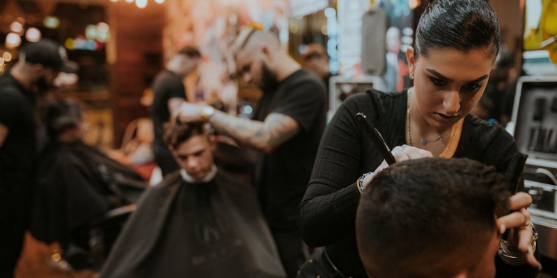 Hairdresser in men's hair salon working on client using hairdresser career advice